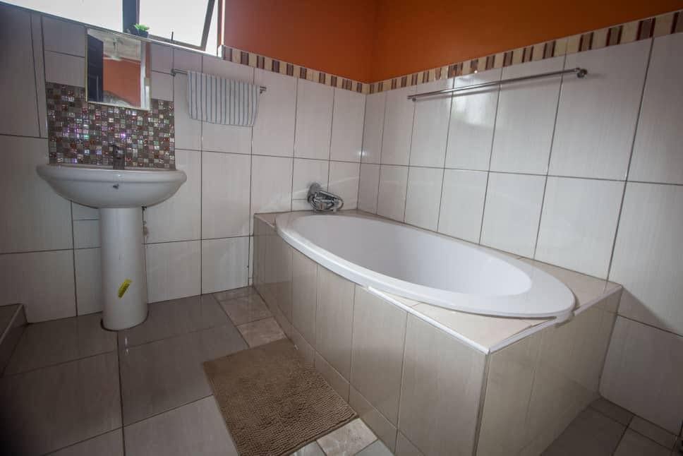 Bathroom with a deep white bath, a pedestal basin and a mosaic splashback