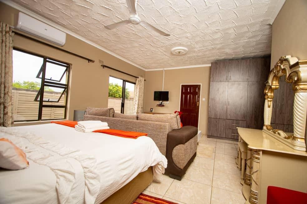 Second bedroom with a large bed, a sofa, a wardrobe, a gold dressing table and air conditioning